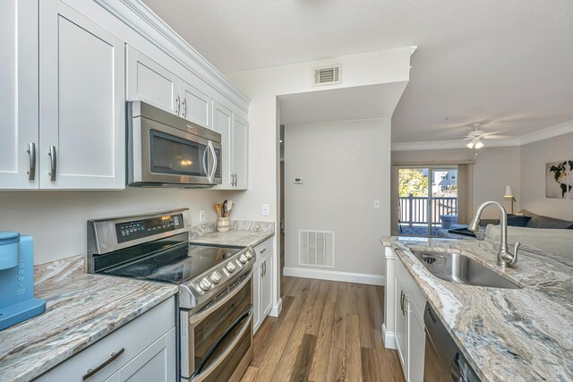 kitchen featuring visible vents, appliances with stainless steel finishes, crown molding, and a sink