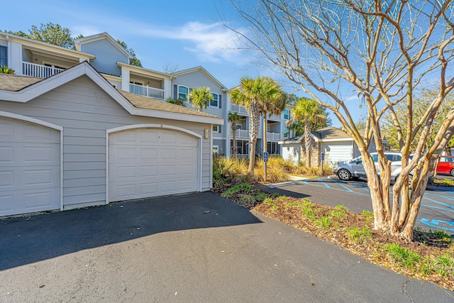 townhome / multi-family property featuring a residential view, driveway, and roof with shingles