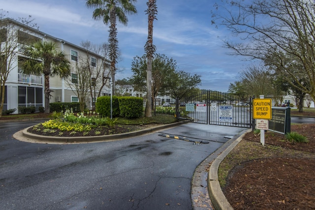 view of street featuring traffic signs, curbs, a gate, a gated entry, and a residential view