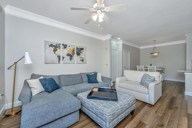 living room featuring a ceiling fan, wood finished floors, baseboards, and ornamental molding