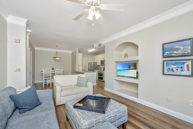 living room featuring baseboards, built in shelves, wood finished floors, and crown molding