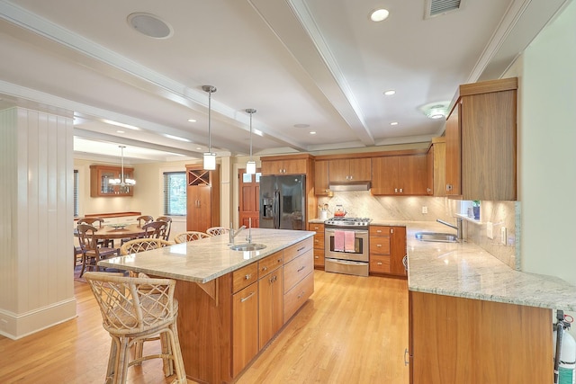 kitchen with pendant lighting, gas stove, beamed ceiling, black fridge, and a center island with sink