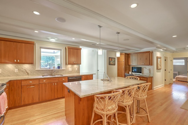 kitchen with sink, pendant lighting, light hardwood / wood-style floors, and a kitchen island with sink