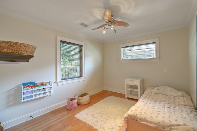 bedroom featuring ceiling fan, crown molding, multiple windows, and hardwood / wood-style flooring