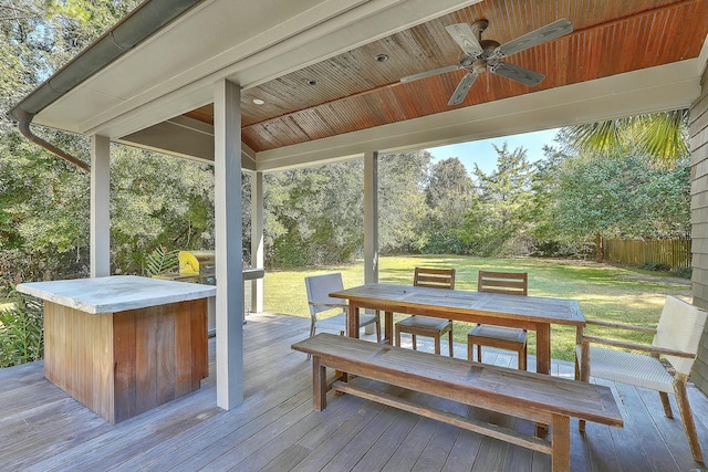 wooden deck featuring ceiling fan, a lawn, and grilling area