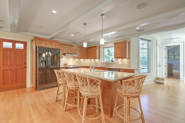 kitchen featuring light hardwood / wood-style floors, hanging light fixtures, black appliances, beam ceiling, and a center island