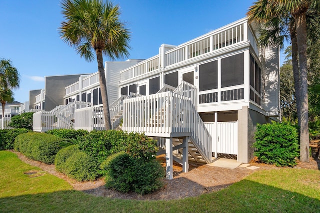 rear view of house featuring a yard, a wooden deck, and a sunroom