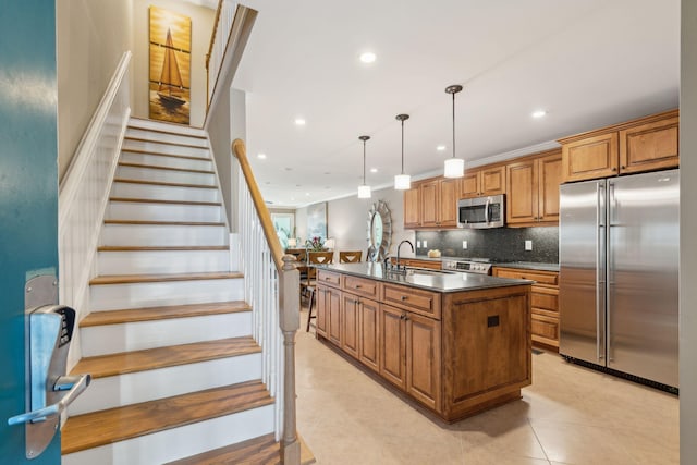 kitchen featuring tasteful backsplash, appliances with stainless steel finishes, sink, hanging light fixtures, and a kitchen island with sink