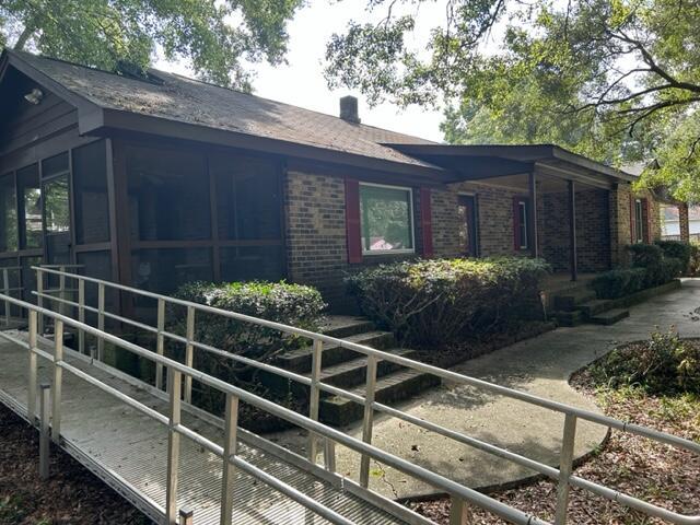 view of property exterior featuring a sunroom, brick siding, and a chimney