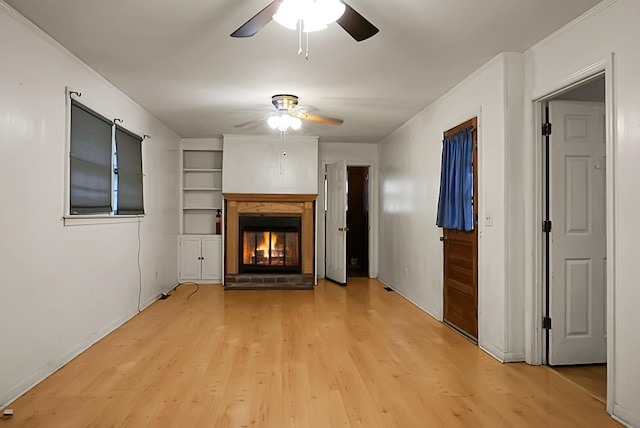 unfurnished living room featuring ornamental molding, light wood-type flooring, ceiling fan, and a brick fireplace