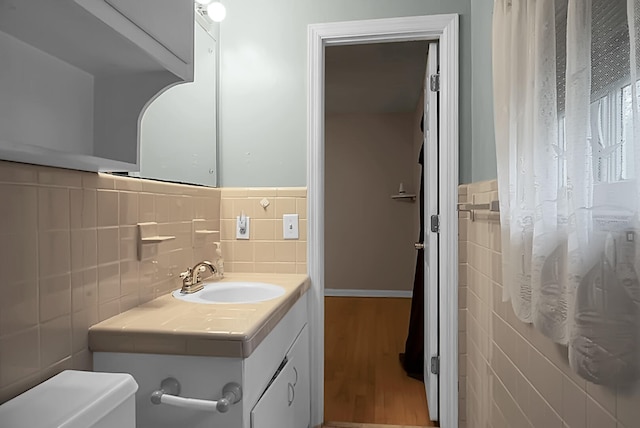 bathroom featuring wood-type flooring, toilet, and tile walls