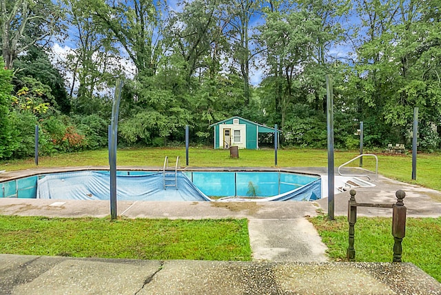 view of pool with an outbuilding and a yard