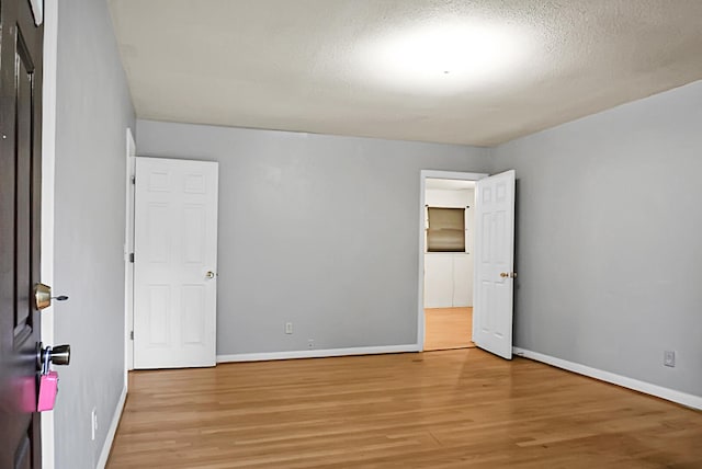 spare room featuring light hardwood / wood-style floors and a textured ceiling