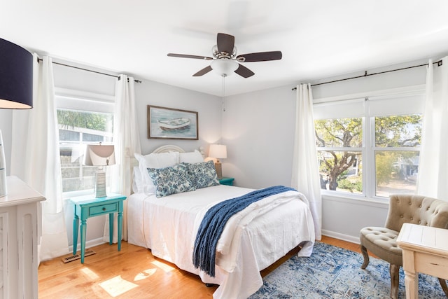 bedroom featuring a ceiling fan, multiple windows, and wood finished floors