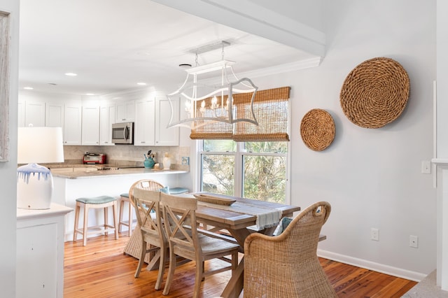 dining space with recessed lighting, an inviting chandelier, light wood-style flooring, baseboards, and ornamental molding