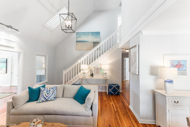 living room with wood finished floors, a chandelier, baseboards, stairway, and high vaulted ceiling