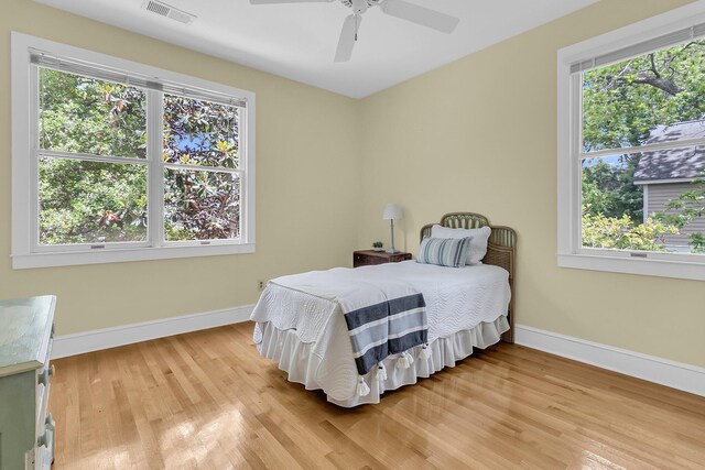 bedroom with light wood finished floors, baseboards, and ceiling fan