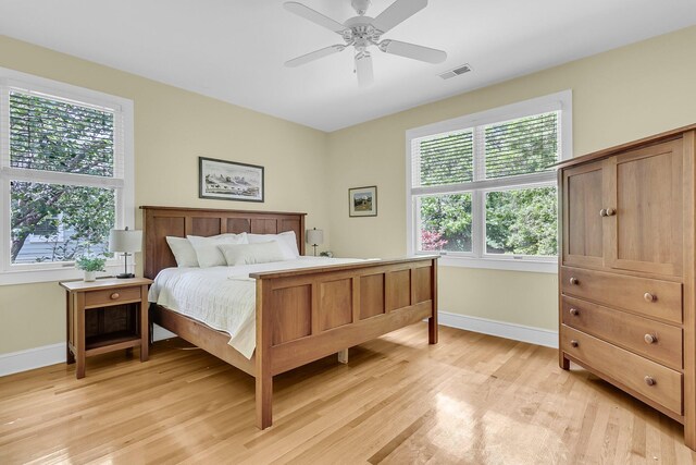 bedroom featuring baseboards, multiple windows, and light wood-type flooring