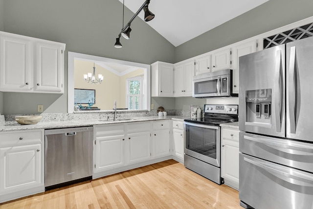 kitchen featuring stainless steel appliances, lofted ceiling, a sink, a chandelier, and white cabinetry