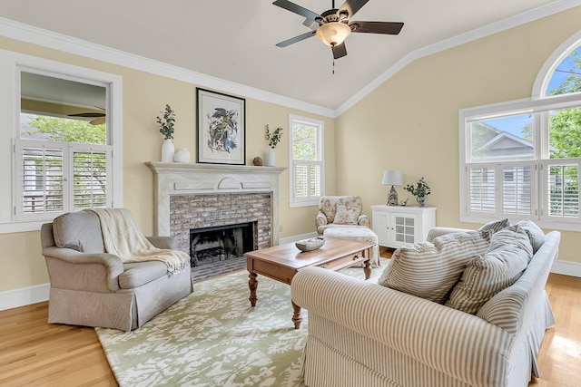 living area with ceiling fan, wood finished floors, plenty of natural light, vaulted ceiling, and crown molding