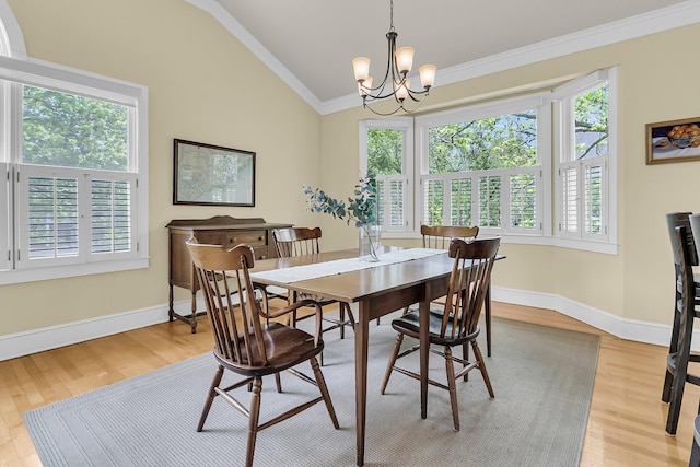 dining room featuring lofted ceiling, crown molding, light wood-style flooring, a chandelier, and baseboards