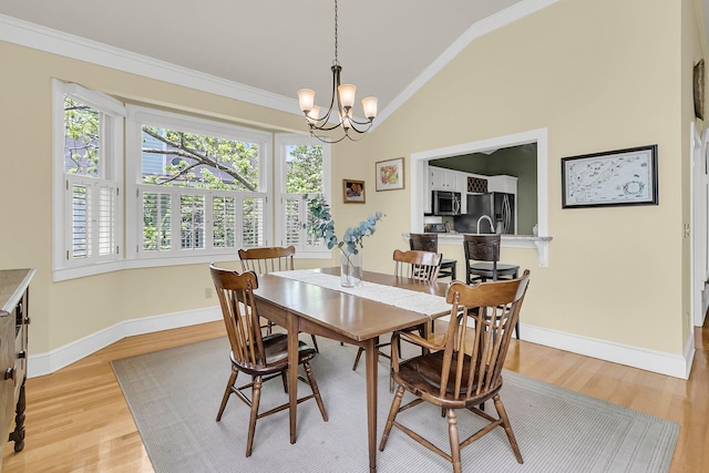 dining space featuring lofted ceiling, crown molding, light wood-style flooring, baseboards, and a chandelier