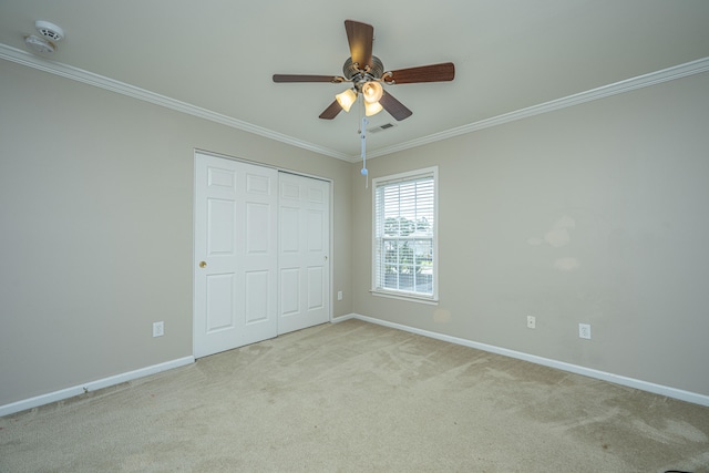 unfurnished bedroom with a closet, ceiling fan, light colored carpet, and crown molding