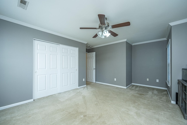 unfurnished bedroom featuring a closet, light colored carpet, ornamental molding, and ceiling fan