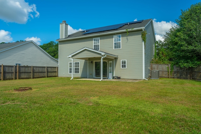 rear view of property featuring a yard, central AC unit, a patio, solar panels, and a fire pit