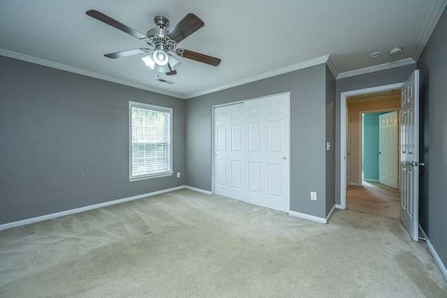 unfurnished bedroom with crown molding, ceiling fan, a closet, and light carpet