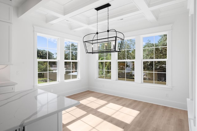 unfurnished dining area with beamed ceiling, coffered ceiling, and light hardwood / wood-style flooring