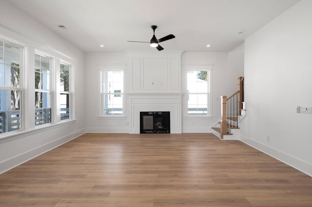 unfurnished living room with ceiling fan, a fireplace, and light hardwood / wood-style flooring