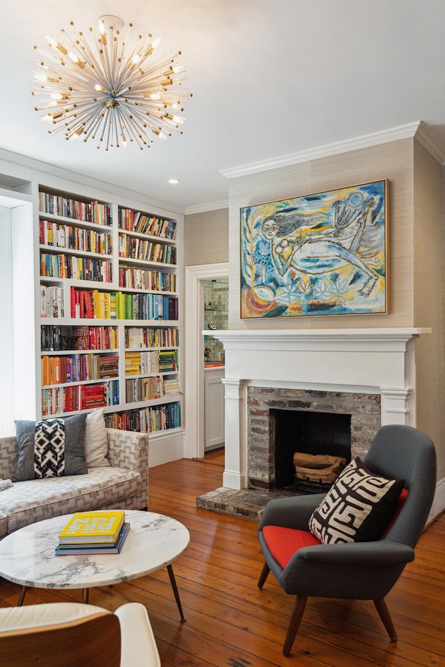 sitting room featuring hardwood / wood-style flooring, a fireplace, ornamental molding, and a chandelier