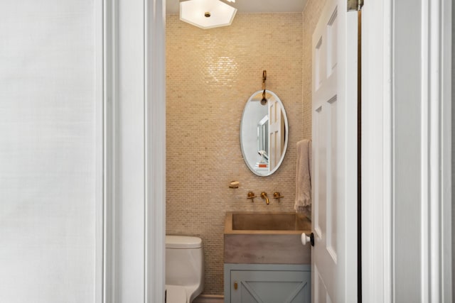 bathroom with vanity, tile walls, and toilet