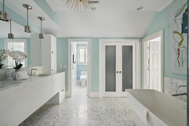 bathroom featuring lofted ceiling, vanity, toilet, a bath, and french doors