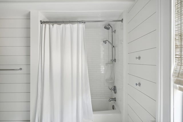 bathroom with shower / bathtub combination with curtain and wood walls