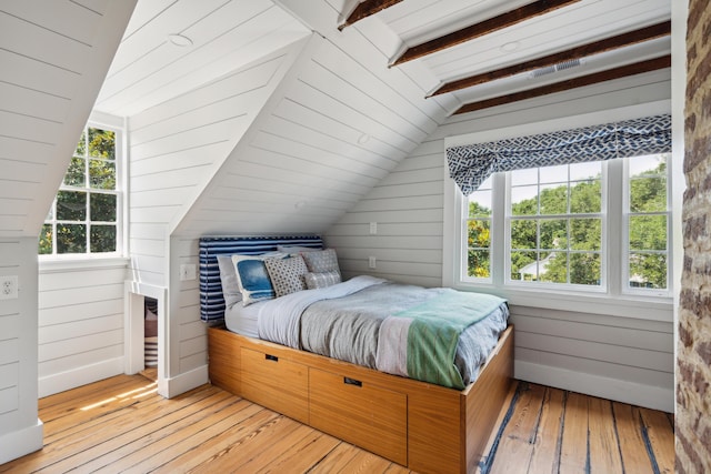 bedroom featuring wooden walls, lofted ceiling with beams, and wood-type flooring