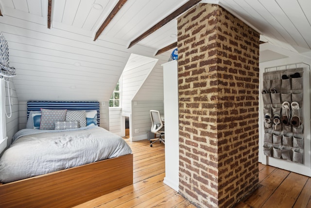 bedroom featuring wooden walls, hardwood / wood-style floors, and vaulted ceiling with beams