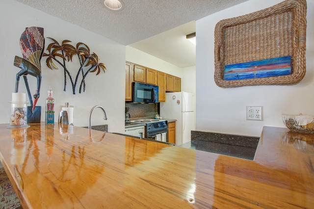 kitchen featuring sink, white refrigerator, range with electric stovetop, backsplash, and a textured ceiling