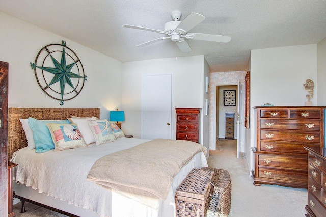 bedroom featuring ceiling fan, light colored carpet, and a textured ceiling