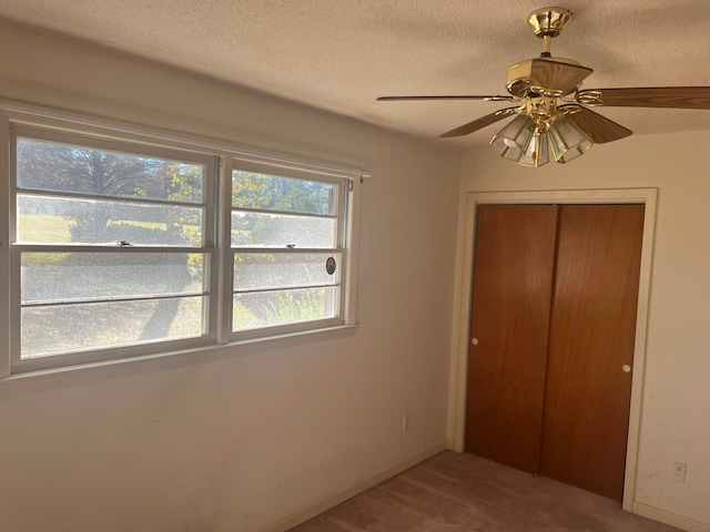 unfurnished bedroom with ceiling fan, a textured ceiling, and a closet