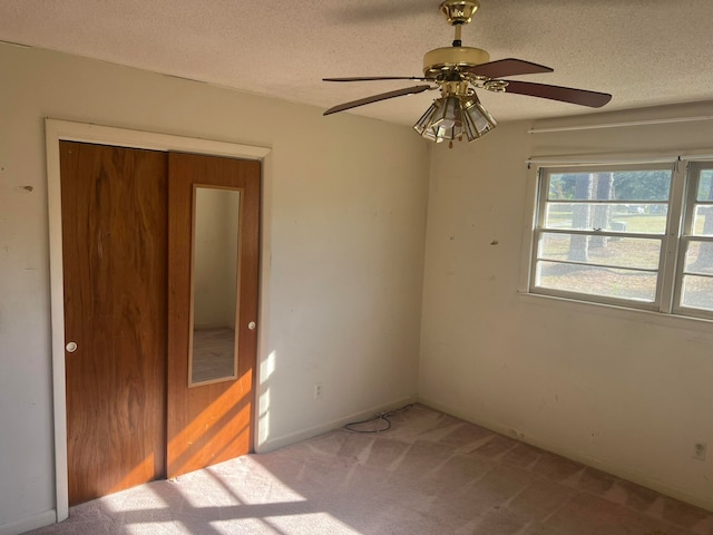 spare room with ceiling fan, a textured ceiling, and light carpet