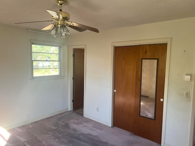 unfurnished bedroom featuring a textured ceiling, carpet floors, a closet, and ceiling fan