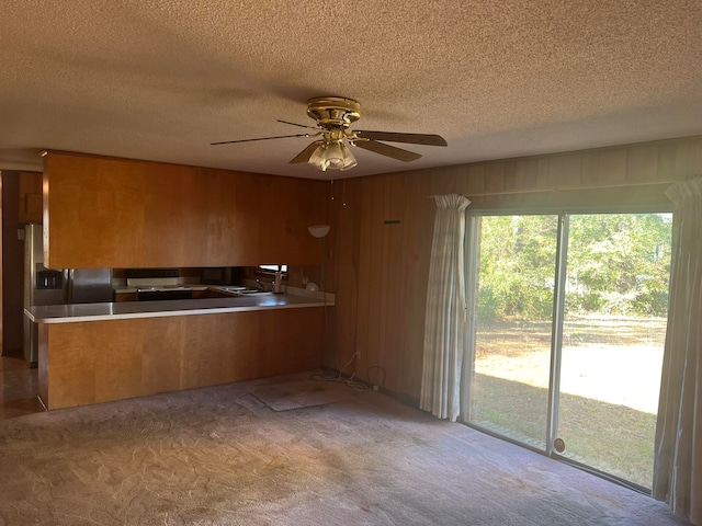 kitchen with stainless steel fridge with ice dispenser, wooden walls, ceiling fan, and light colored carpet