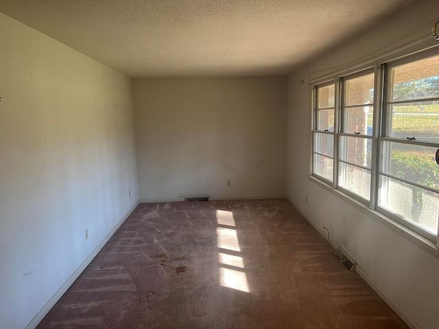 spare room featuring dark carpet and a textured ceiling