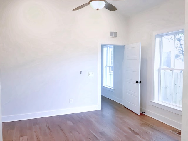 empty room with ceiling fan, a wealth of natural light, and hardwood / wood-style floors