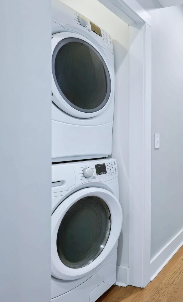 laundry room featuring stacked washing maching and dryer and light wood-type flooring