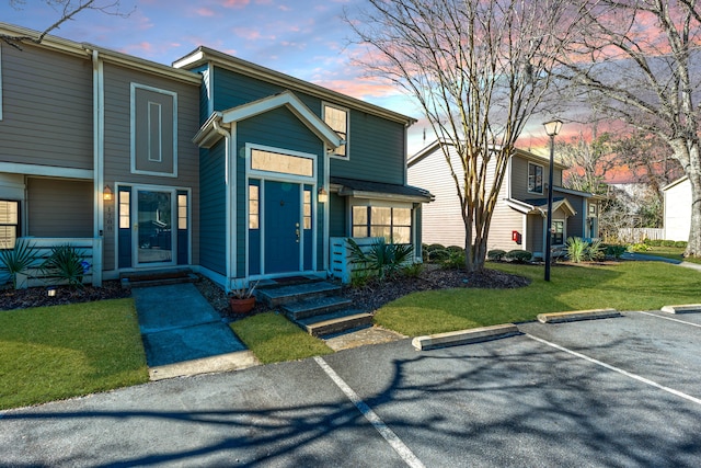 view of front facade with uncovered parking and a front lawn