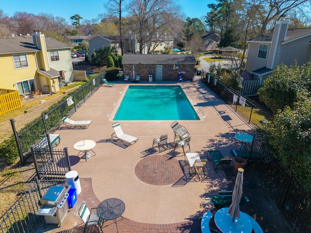 pool with a patio area, fence, and a residential view