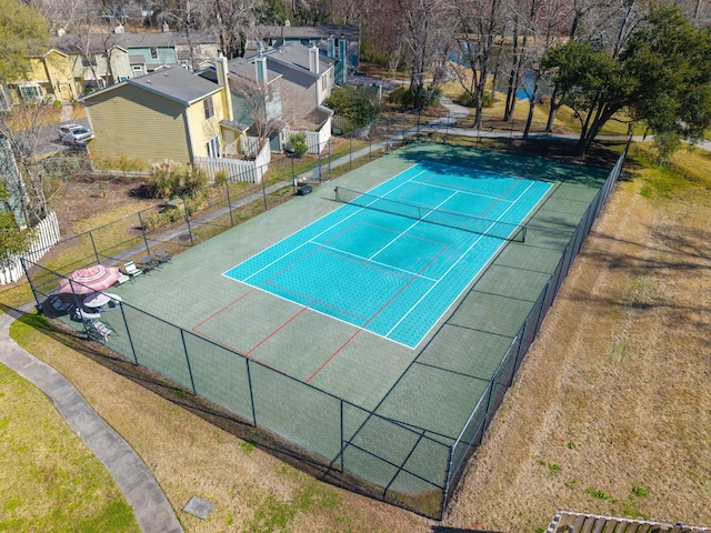 view of tennis court featuring fence and a residential view